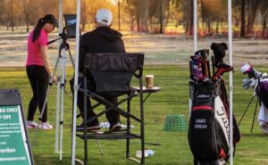 Golf coach and student reviewing practice at an outdoor driving range.
